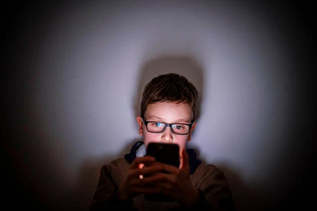 Symbolfoto. Gestellte Aufnahme zum Thema Kinder nutzen Social Media. Ein Junge sitzt in einem dunklen Raum und wird von einem Smartphone beleuchtet. Berlin, 16.02.2026. Berlin Deutschland *** Symbol photo Staged photo on the topic of children using social media A boy sits in a dark room and is illuminated by a smartphone Berlin, 16 02 2026 Berlin Germany Copyright: xThomasxTrutschelx