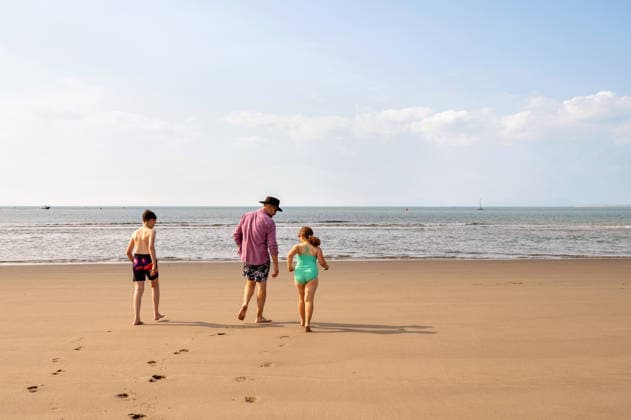 back view of single father with kids walking on beach to the sea. Wales, England, United Kingdom R_JNDO260222-1935004-01 ,model released, Symbolfoto
