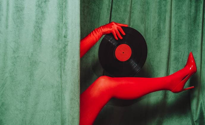 Red gloved hand and leg with vinyl record and high heel by green velvet curtain model released, Symbolfoto, AAF00145