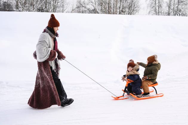 Young family playing together outdoors in winter pulling sled in snow model released, Symbolfoto, EYAF03836