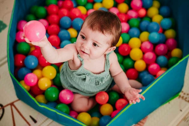 Baby playing with colorful pool balls at home and smiling model released, Symbolfoto property released, EBBF09317