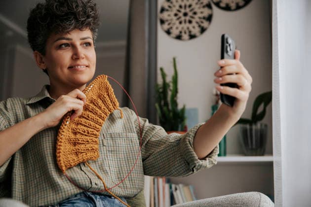 Woman knitting with warm wool and taking a selfie at home model released, Symbolfoto, HDF00251