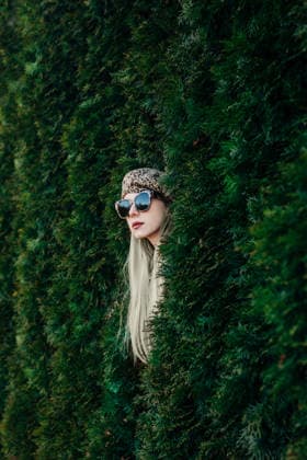 Stylish woman with sunglasses and leopard jacket posing by thuja hedge model released, Symbolfoto, VSNF04570
