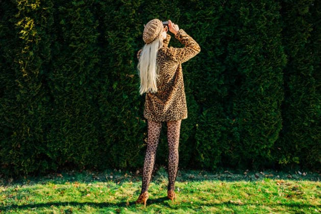 Stylish person in leopard jacket taking photographs in garden outdoors model released, Symbolfoto, VSNF04572