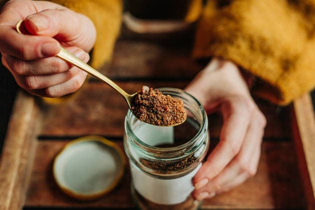 Hand holding spoon with propolis above glass jar of natural remedy model released, Symbolfoto, VSNF04574
