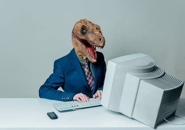Person in business suit with dinosaur head working on old computer model released, Symbolfoto, VSNF04599