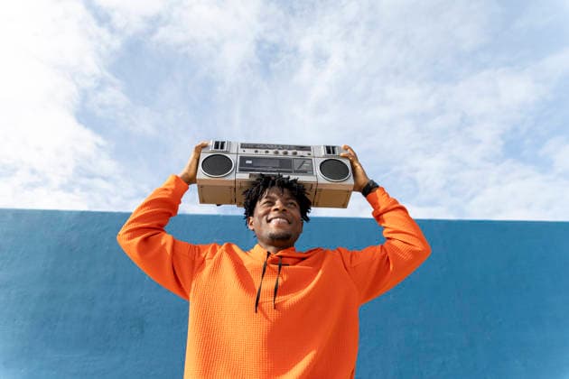 Person in orange holding boombox overhead smiling in Barcelona outdoors model released, Symbolfoto, YPF00087