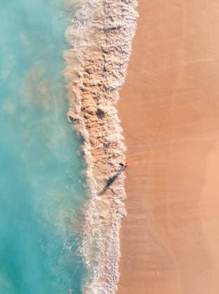 Aerial view of woman walking from beach into turquoise ocean waters. Grace Bay, Caicos Islands, Turks and Caicos Islands CR_DOHO260224B-1973408-01 ,model released, Symbolfoto
