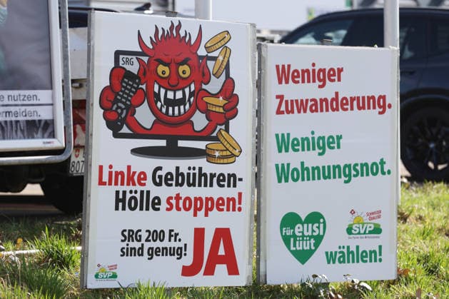 25.02.2026 Ruemlang ZH, SCHWEIZ, Ein Ja Plakat zur SRG-Initiative (Halbierungsinitiative) am Strassenrand. Und ein SVP Plakat Weniger Zuwanderung, Weniger Wohnungsnot. *** 25 02 2026 Ruemlang ZH, SWITZERLAND, A Yes poster for the SRG initiative halving initiative on the roadside and an SVP poster Less immigration, less housing shortage 