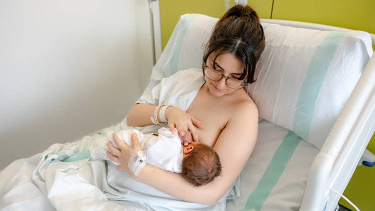 Mother bonding with newborn in hospital setting A mother lovingly cradles her newborn baby while breastfeeding in a hospital bed. The tender moment captures the early bonding and nurturing care in a healthcare environment. Model Released SilviaRedondo_ID32037_1090619_017 Copyright: xSilviaxRedondox RECORD DATE NOT STATED