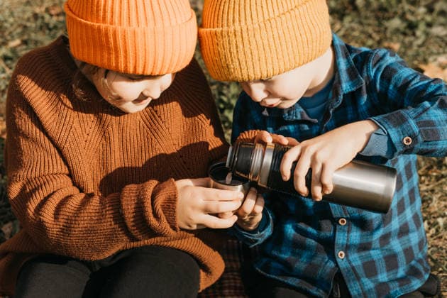 Children enjoying autumn warmth in forest adventure Two children dressed in cozy autumn attire share a warm beverage from a thermos during a forest adventure, capturing the warmth and joy of a mini journey in a lush autumn setting. Model Released ZulfiiaIshmukhametova_ID32754_1115172_011 Copyright: xZulfiiaxIshmukhametovax RECORD DATE NOT STATED