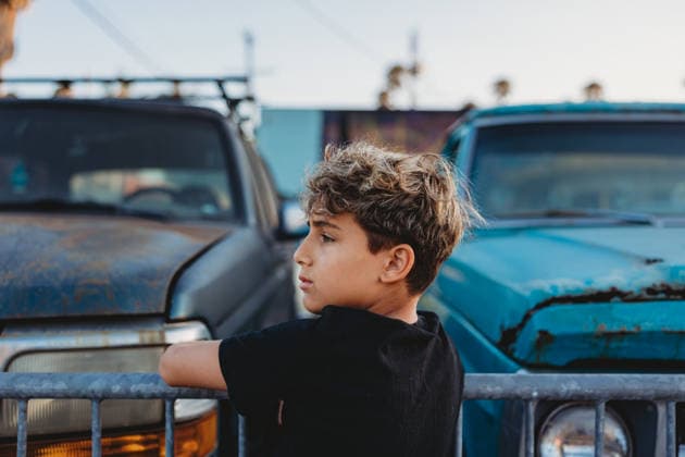Boy on a fence with old cars on the other side. United States, California, San Diego CR_CHDO260218-1944906-01 ,model released, Symbolfoto