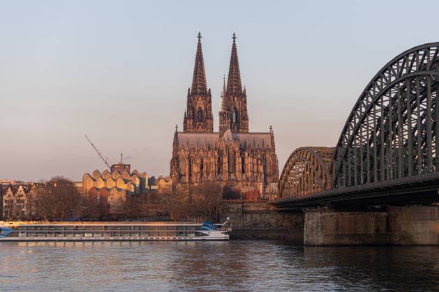 Sonnenaufgang in Köln. Blick vom Deutzer Ufer über den Rhein auf den Kölner Dom und die Hohenzollernbrücke. Die ersten Sonnenstrahlen tauchen die Kathedrale in warmes Morgenlicht. Gleichzeitig spiegelt sich das Licht in der markanten Fassade des Museum Ludwig neben dem Dom. Köln Deutz Nordrhein-Westfalen Deutschland *** Sunrise in Cologne View from the Deutz riverbank across the Rhine to Cologne Cathedral and the Hohenzollern Bridge The first rays of sunlight bathe the cathedral in warm morning light At the same time, the light is reflected in the striking façade of the Museum Ludwig next to Cologne Cathedral Deutz North Rhine-Westphalia Germany Copyright: xMarcxJohnx