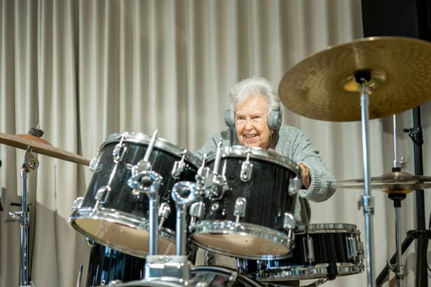 Senior woman enjoying her hobby playing drums. Senior woman enjoying her hobby playing drums. Retired musician. model released