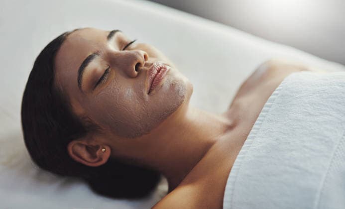Woman, relax and spa with facial mask for skincare, exfoliation or cleanse on massage bed. Top view, female person or sleeping with face treatment or moisturizer for pamper in beauty salon at resort. model released property released Copyright: xwww.peopleimages.comx