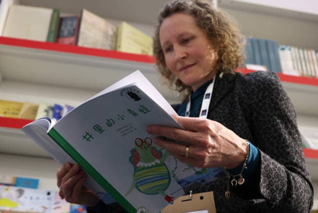 (260311) -- LONDON, March 11, 2026 -- A woman reads at the China Pavilion of the 2026 London Book Fair in London, Britain, March 10, 2026. At Olympia London, where the 2026 London Book Fair opened Tuesday, the China pavilion stands out not merely for its expansive footprint, but for the comprehensive publishing ecosystem it showcases. The Chinese publishing delegation has arrived with an impressive portfolio of over 4,000 titles and a packed schedule of more than 40 events. Spanning the three-day fair, the agenda ranges from high-profile new book launches and author talks to rights exchanges and industry forums. TO GO WITH Feature: Two-way street -- China s delegation highlights cultural synergy, tech fusion at London Book Fair ) B