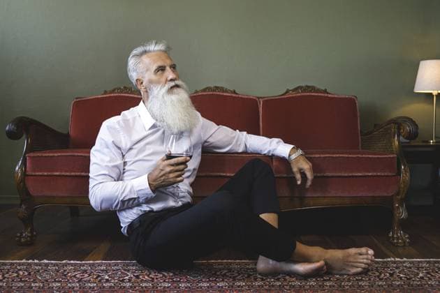 Stilvoller und gutaussehender bärtiger Senior, der auf dem Boden sitzt und Rotwein trinkt Stylish and handsome bearded senior man sitting on the floor and drinking red wine Copyright: imageBROKER blackday ibxiqx16979749.jpg ,model released, Symbolfoto ,property released