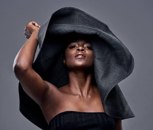 High fashion, portrait or black woman in studio with hat, luxury or oversized accessory in editorial attire. Creative, wide brim or person with fedora, elegant or glamour aesthetic on gray background. model released property released Copyright: xwww.peopleimages.comx