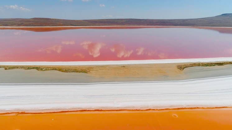 Creative Highlights World Blick von oben auf Wolken, die sich im rosa See spiegeln. Aufnahme. Leuchtend orangefarbene und rosa Seen werden durch weiße Ufer voneinander getrennt. Wunderschöne Spiegelung von Wolken und blauem Himmel im rosa See. Top view of clouds reflected in pink lake. Shot. Bright colorful orange and pink lakes are separated by white shore. Beautiful reflection of clouds and blue sky in pink lake. (License=RF) Copyright: xZoonar.com MziyaxKashakhix 24797776