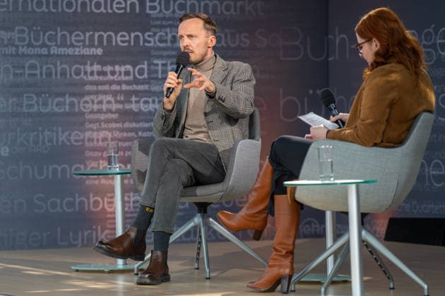 Leipzig - Volle Hallen zum letzten Messetag: Abschluss auf der Leipziger Buchmesse 22.03.2026¨Leipzig, Messe-Allee (Leipziger Messe) im Foto: Michal Hvorecky mit seinem Buch Dissident auf der Bühne von ARD, ZDF und 3sat in der Glashalle ¨Am Sonntag hat die Leipziger Buchmesse noch einmal zahlreiche Besucher auf das Messegelände gelockt und einen lebendigen Abschluss des diesjährigen Events geboten. Besonders Familien, Literaturfans und Cosplay-Begeisterte nutzten den letzten Messetag, um durch die Hallen zu schlendern, Neuerscheinungen zu entdecken und Autorinnen und Autoren hautnah zu erleben. Neben gut besuchten Lesungen und Signierstunden stand vor allem der Austausch im Mittelpunkt: Gespräche über aktuelle gesellschaftli Copyright: xEHLxMedia Erik-HolmxLanghofx 20260322_buchmesse-leipzig-sonntag_68