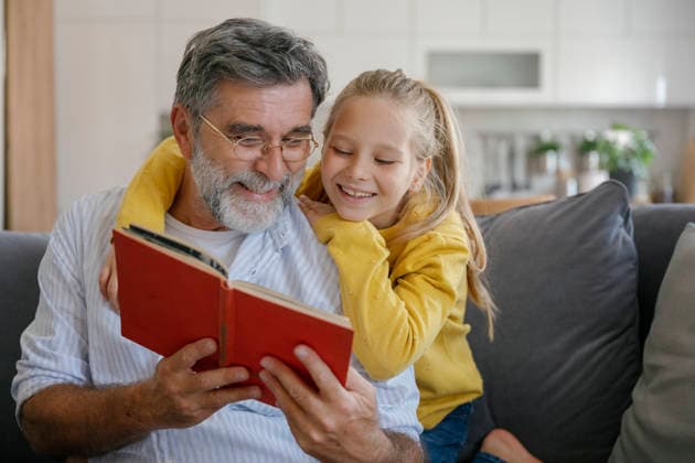 Grandfather and child reading book and hugging on couch indoors model released, Symbolfoto property released, FLMZF03119