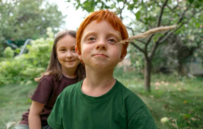 Red-haired child and friend smiling together outdoors in a garden model released, Symbolfoto, MBLF01180