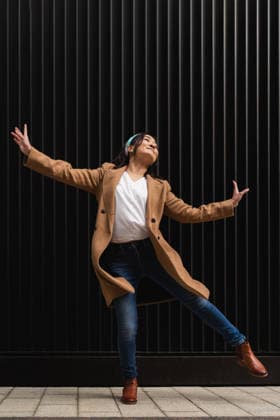 Woman dancing joyfully outdoors in urban setting wearing coat model released, Symbolfoto, PLF00065