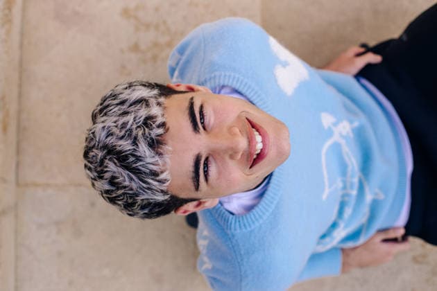 Joyful young man sitting on outdoor steps smiling at camera model released, Symbolfoto, STIF00020