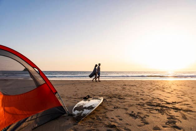 Couple walking with surfboard by tent on beach at sunset model released, Symbolfoto, UUF36535