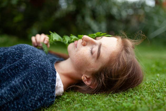 Freckled face person lying on grass with fern relaxing outdoors in summer model released, Symbolfoto, VCF01409