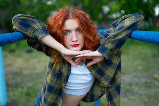 Red haired woman posing on parallel bars at old playground outdoors model released, Symbolfoto, VCF01445