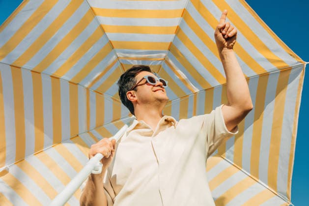 Smiling man in sunglasses under striped umbrella on sunny summer day model released, Symbolfoto, VSNF04729
