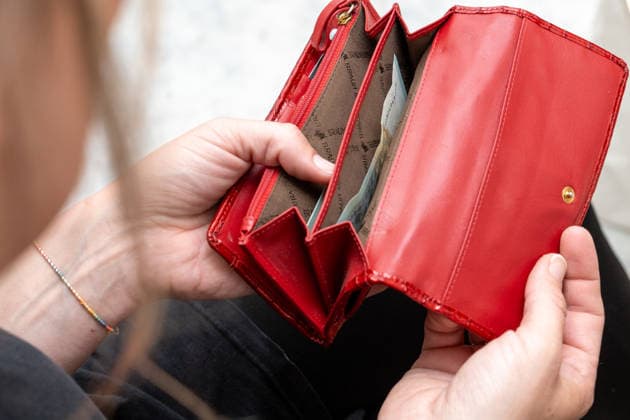 Bavaria, Germany - March 25, 2026: A woman looks into her almost empty purse, symbolizing the rising cost of living, inflation and financial worries in everyday life