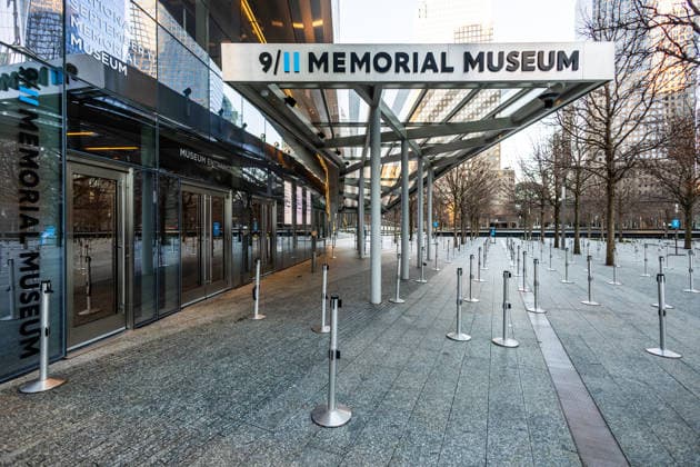 Eingangsbereich des 9 11 Memorial Museums am World Trade Center in Lower Manhattan, New York City. Die moderne Architektur mit Glas- und Metallstrukturen wird vom frühen Morgenlicht beleuchtet, während die Absperrungen und Wegeführungen vor dem Eingang eine ruhige und geordnete Atmosphäre schaffen. Die Aufnahmen zeigen einen bedeutenden Erinnerungsort sowie zeitgenössische Architektur im Financial District. *** Entrance area of the 9 11 Memorial Museum at the World Trade Center in Lower Manhattan, New York City The modern architecture with glass and metal structures is illuminated by the early morning light, while the barriers and pathways in front of the entrance create a calm and orderly atmosphere The photographs show an important