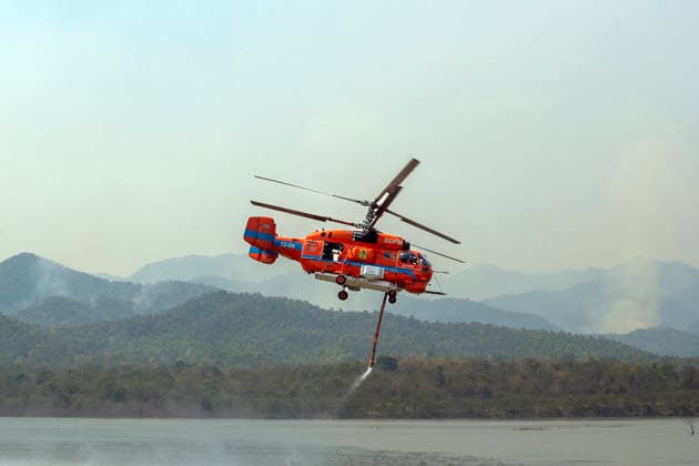 Helicopters Battle Wildfires in Chiang Mai, Thailand - 27 Mar 2026 A helicopter performs water pickup operations over a reservoir in Chiang Mai, northern Thailand, as part of aerial firefighting efforts against ongoing wildfires. A KA-32 helicopter from the Department of Disaster Prevention and Mitigation skims the water surface to collect water before heading to fire-affected forest areas amid hazy conditions caused by smoke and rising PM2.5 pollution. Chiang Mai Thailand Copyright: xPongmanatxTasirix xSOPAxImagesx PTASIRI270326DxII4904