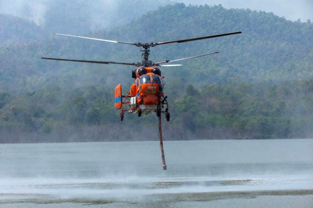Helicopters Battle Wildfires in Chiang Mai, Thailand - 27 Mar 2026 A helicopter performs water pickup operations over a reservoir in Chiang Mai, northern Thailand, as part of aerial firefighting efforts against ongoing wildfires. A KA-32 helicopter from the Department of Disaster Prevention and Mitigation skims the water surface to collect water before heading to fire-affected forest areas amid hazy conditions caused by smoke and rising PM2.5 pollution. Chiang Mai Thailand Copyright: xPongmanatxTasirix xSOPAxImagesx PTASIRI270326R6II5763