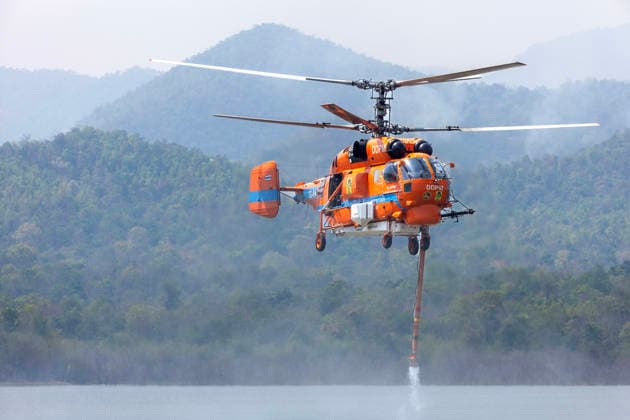 March 27, 2026, Chiang Mai, Thailand: A helicopter performs water pickup operations over a reservoir in Chiang Mai, northern Thailand, as part of aerial firefighting efforts against ongoing wildfires. A KA-32 helicopter from the Department of Disaster Prevention and Mitigation skims the water surface to collect water before heading to fire-affected forest areas amid hazy conditions caused by smoke and rising PM2.5 pollution. Chiang Mai Thailand  - ZUMAs197 20260327_aaa_s197_342 Copyright: xPongmanatxTasirix