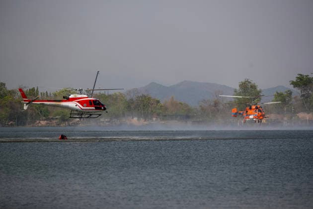 March 27, 2026, Chiang Mai, Thailand: Two helicopters perform water pickup operations over a reservoir in Chiang Mai, northern Thailand, as part of aerial firefighting efforts against ongoing wildfires. An AS350 helicopter from the Ministry of Natural Resources and Environment (left) and a KA-32 helicopter from the Department of Disaster Prevention and Mitigation (right) skim the water surface to collect water before heading to fire-affected forest areas amid hazy conditions caused by smoke and rising PM2.5 pollution. Chiang Mai Thailand - ZUMAs197 20260327_aaa_s197_319 Copyright: xPongmanatxTasirix