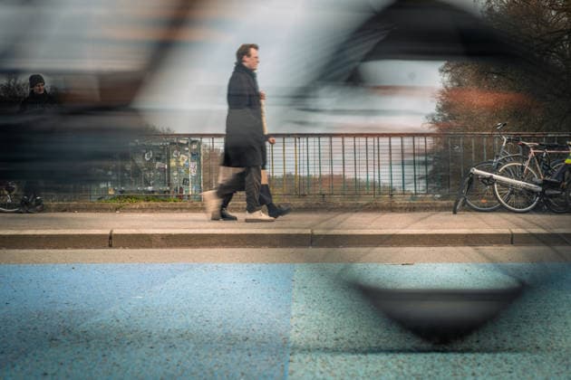 Ein flüchtiger Moment im urbanen Alltag: Während eine vorbeieilende Person in Bewegungsunschärfe verschwindet, bleiben abgestellte Fahrräder als ruhiger Kontrast am Straßenrand zurück. Motion *** A fleeting moment in everyday urban life While a person hurrying past disappears in a blur of motion, parked bicycles remain as a quiet contrast at the side of the road Motion