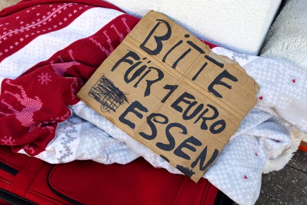 Obdachlosigkeit - BITTE FÜR 1 EURO ESSEN - Zwei Pappbecher für evtl. Spenden - Lebenswelt von Menschen ohne festen Wohnsitz - 06.03.2026, Fulda, Deutschland, GER, DEU - Roter Koffer mit div. Habseligkeiten eines offenbar wohnungslosen Menschen in der kalten Jahreszeit am Straßenrand . Er bittet vorbeikommende Mitbürger um eine Spende für Nahrung. Immer mehr Menschen leben in Deutschland ohne festen Wohnsitz auf der Straße. *** Homelessness PLEASE EAT FOR 1 EURO Two paper cups for possible donations Living environment of people without a fixed abode 06 03 2026, Fulda, Germany, GER, DEU Red suitcase with various belongings of an apparently homeless person on the side of the road in the cold season He asks passing fellow citizens for a donati