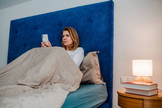 Nighttime routine for mature woman, scrolling on phone. Nighttime routine for mature woman, scrolling on phone in bed. model released