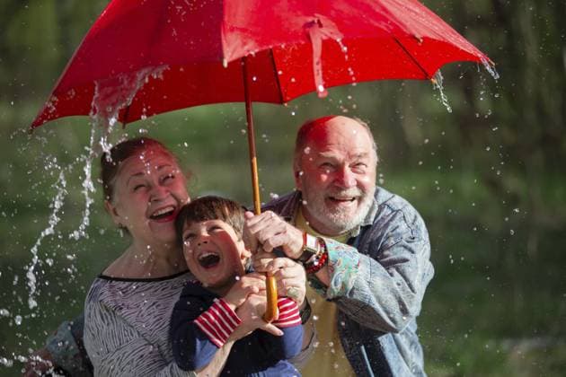 Großvater und Enkel halten einen Regenschirm in der Hand, und Großmutter schaut sie an. Die Szene ist lustig und unbeschwert. Familie im Regen Grandfather and grandson are holding an umbrella, and grandmother is looking at them. The scene is fun and light-hearted. family in the rain Copyright: imageBROKER Svetlana ibxiqx17101662.jpg ,model released, Symbolfoto ,property released