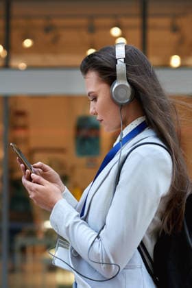 Scroll, smartphone and businesswoman with headphones in city, commute and communication with contact. Outdoor, commuter and person with mobile for message, reading and listening to music on walk. model released property released Copyright: x@AILAxIMAGESx