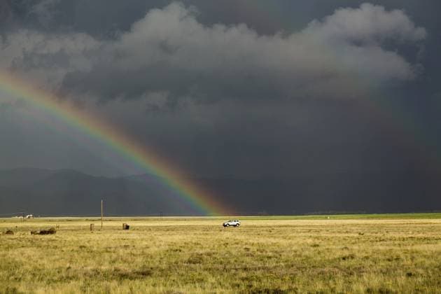 Sonnendurchflutetes Präriegrasenland mit dunklen und unheimlichen Gewitterwolken und Regenguss. Van fährt auf einer einsamen Landstraße und Regenbogen endet über dem Fahrzeug Sun illuminating prairie grassland with dark and forbidding thunderclouds and downpour with van riding along lonely country road and rainbow ending over the vehicle Copyright: imageBROKER StevexHeap ibxiqx17258451.jpg ,model released, Symbolfoto ,property released