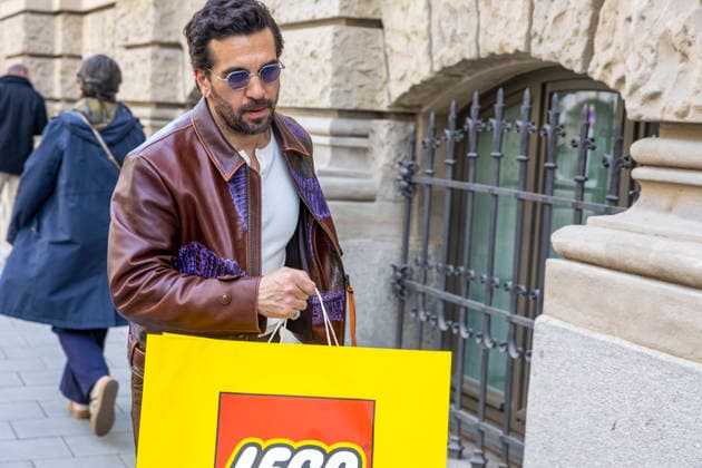 Schauspieler Elyas M Barek kommt mit einer Lego Einkaufstasche aus Papier vom Einkaufen zurück ins Hotel Rosewood Munich in München Datum: 16.04.2026 *** Actor Elyas M Barek returns from shopping to the Rosewood Munich Hotel in Munich with a Lego paper shopping bag Date 16 04 2026