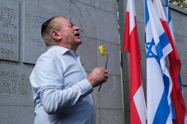 April 19, 2026, Warsaw, Masovian Voivodeship, Poland: A commemorator holding a daffodil sings at the Umschlagplatz Monument in Warsaw during official commemorations of the 83rd anniversary of the outbreak of the Warsaw Ghetto Uprising. The tradition of using yellow daffodils as symbols of remembering Jewish lives lost during the uprising was started by Marek Edelman, one of the commanders of the uprising and a co-founder of the Jewish Combat Organization, an armed anti-fascist Jewish resistance movement instrumental in opposing Nazi rule in the ghetto. Warsaw Poland  - ZUMAk204 20260419_zip_k204_038 Copyright: xRomanxKozielx