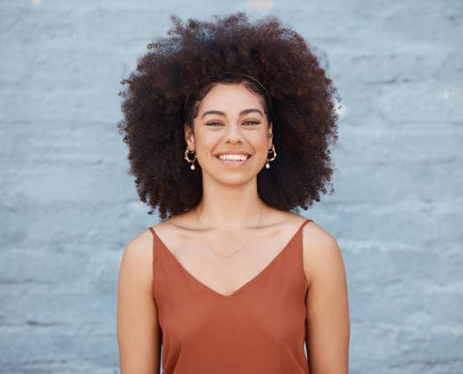 Portrait of cheerful woman with big afro and beautiful smile standing outside against a brick wall. Carefree woman posing outside during the day. (License=RF) ,model released, Symbolfoto  Copyright: xZoonar.com YurixArcursxpeopleimages.comx 18806419 ,model released, Symbolfoto ,property released
