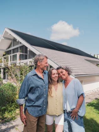 Family with solar panels on house standing together in garden model released, Symbolfoto property released, MFF09874