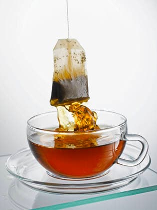 Teabag pulled from glass cup with dripping hot tea, KSWF02505