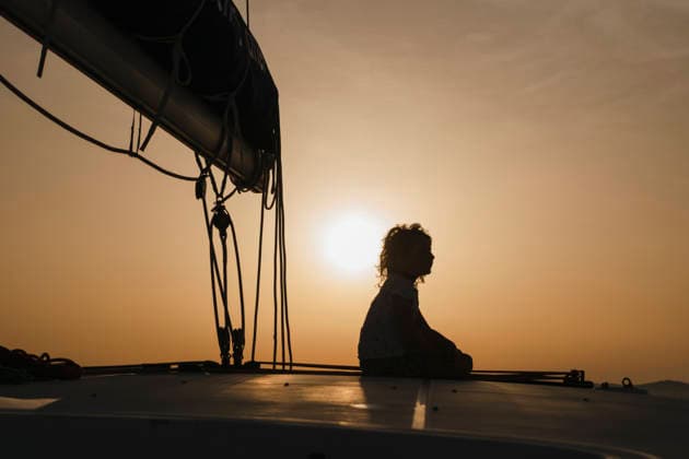 Child sitting on yacht at sunset during family sailing holiday model released, Symbolfoto, NDEF03227